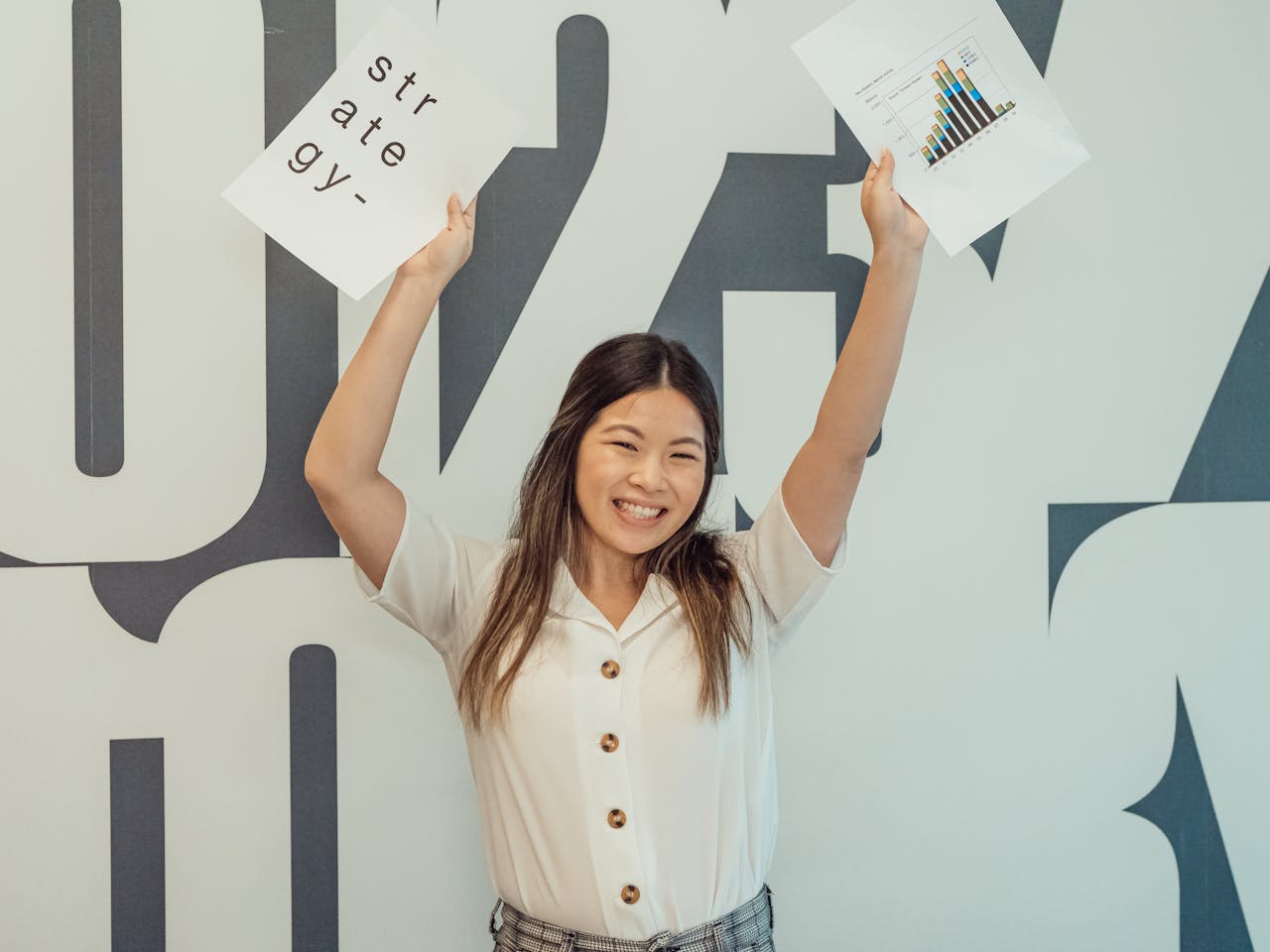 Cheerful woman holding strategy and graph documents in modern office setting.